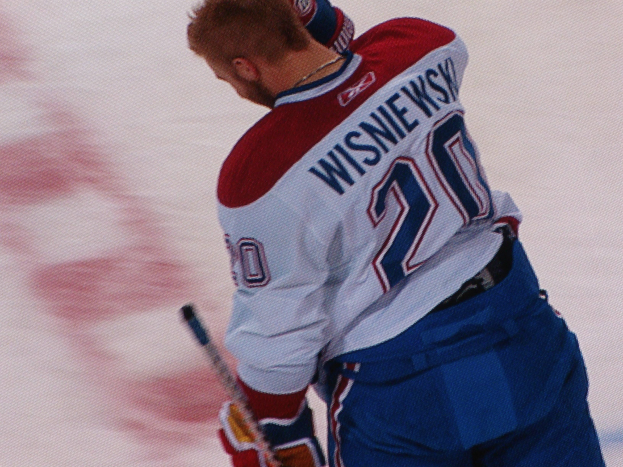 Ein Hockey-Spieler im "Wisniewski"-Trikot steht auf dem Eis und hält einen Hockey-Schläger in der Hand.