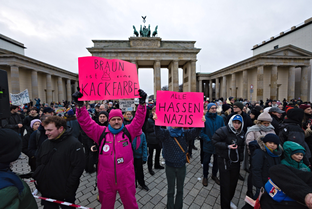 Eine Gruppe von Menschen steht vor dem Reichstag in Berlin, Deutschland, und hält Protestschilder gegen die anti-nazistische Bewegung der deutschen Regierung.