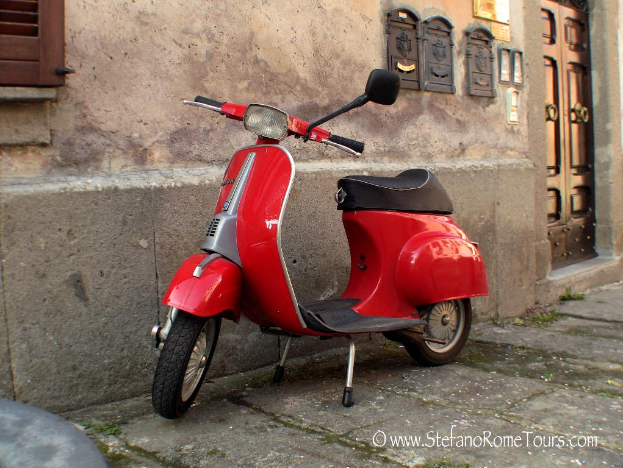 Ein rotes Roller-Fahrzeug ist vor einem Haus mit einer Tür und Fenstern auf einer Straße mit sichtbarem Text geparkt.