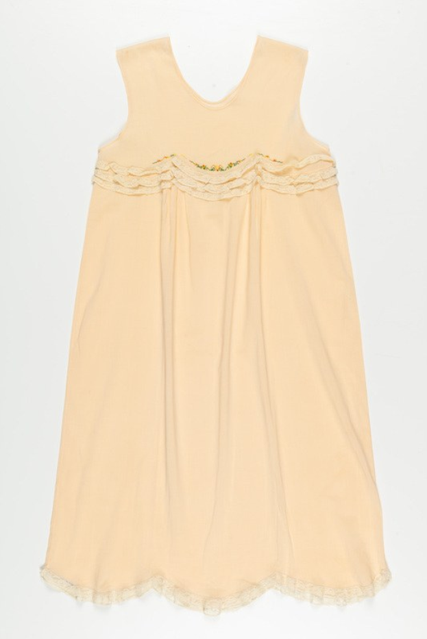 Ein cremefarbenes Nachthemd mit zartem Spitzenbesatz am Halsausschnitt, aus weichem, leichtem Stoff mit einem dezenten Schimmer.