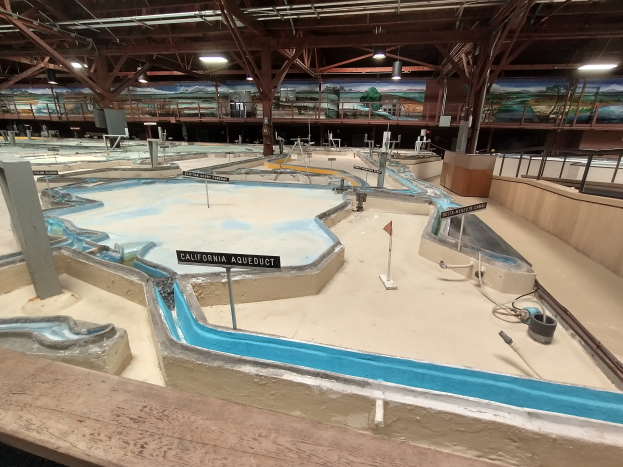 Ein großes Indoor-Wasserpark mit zahlreichen Wasserrutschen, Pfählen, Texttafeln, Deckenlampen und Wandgemälden, das als Minigolfplatz konzipiert ist für einen spaßigen und aufregenden Erlebnis.