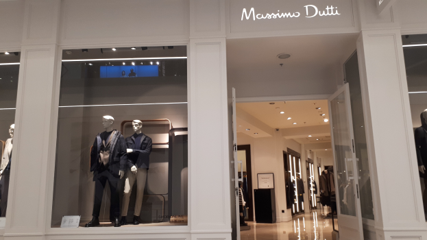 Innenansicht des Massimo Dutti Geschäfts in Mailand mit Schaufensterpuppen in aktueller Mode, Deckenbeleuchtung, Informationsschildern und Türen.
