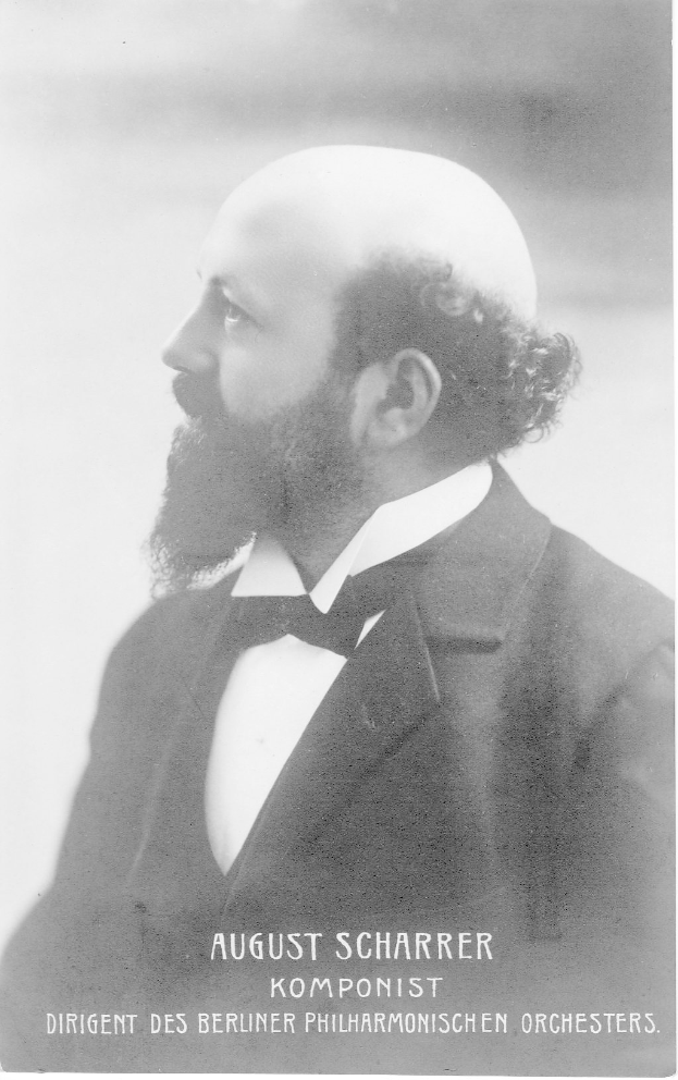 Ein Schwarz-Weiß-Foto von August Scharrer, einem deutschen Komponisten, der einen Blazer und eine Krawatte trägt, mit Text am unteren Bildrand.