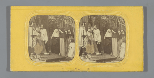 Schwarzes und weißes Foto einer Gruppe von Menschen in traditioneller russischer Kleidung, die auf einer Bühne mit grauem Hintergrund lächeln.