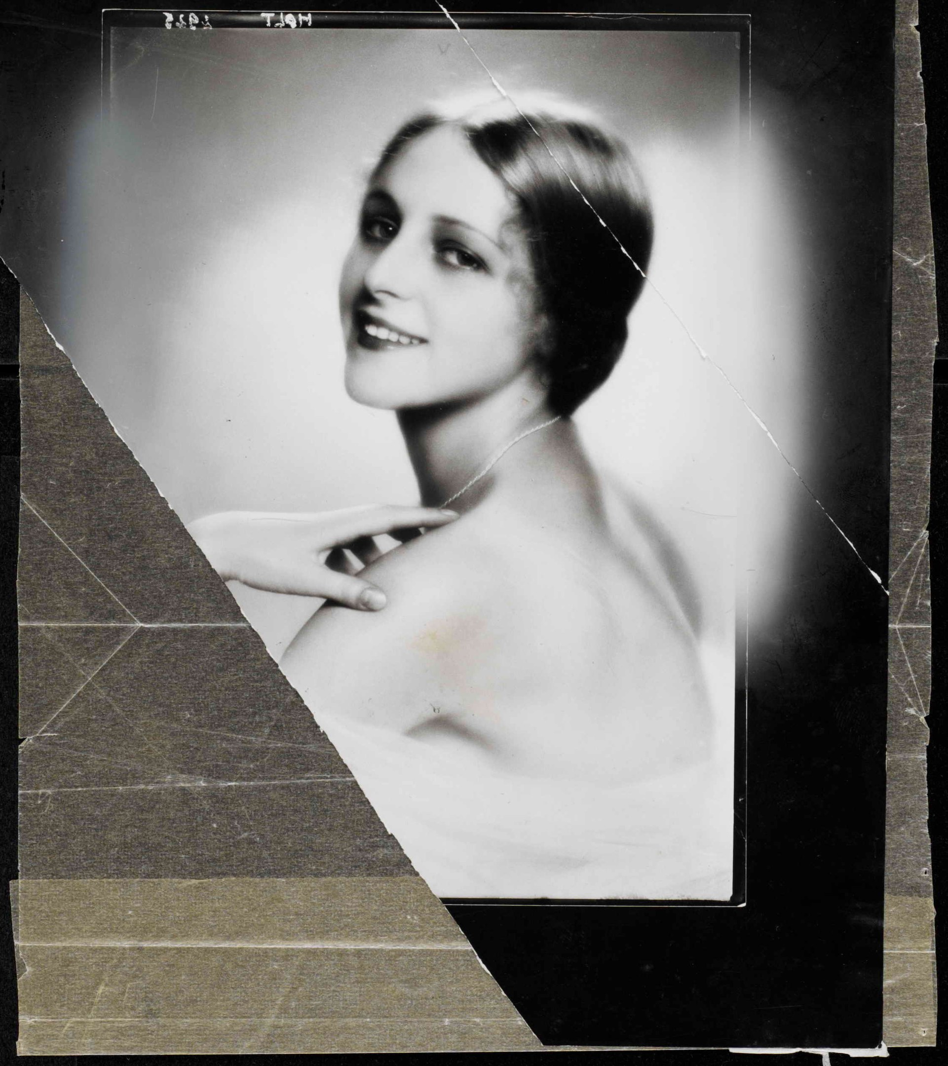 Schwarzes und weißes Porträt einer Frau in einem Kleid im Stil der 1920er Jahre mit einem ordentlichen Dutt, die warm in die Kamera lächelt.