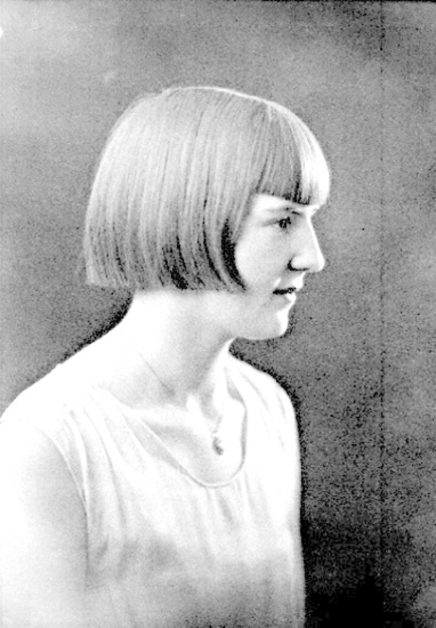 Ein Schwarz-Weiß-Foto einer Frau mit einem kurzen Bob-Haarschnitt, ihr Gesicht ist deutlich zu sehen, ihre Augen schauen zur Seite und ihre Lippen sind leicht geöffnet.