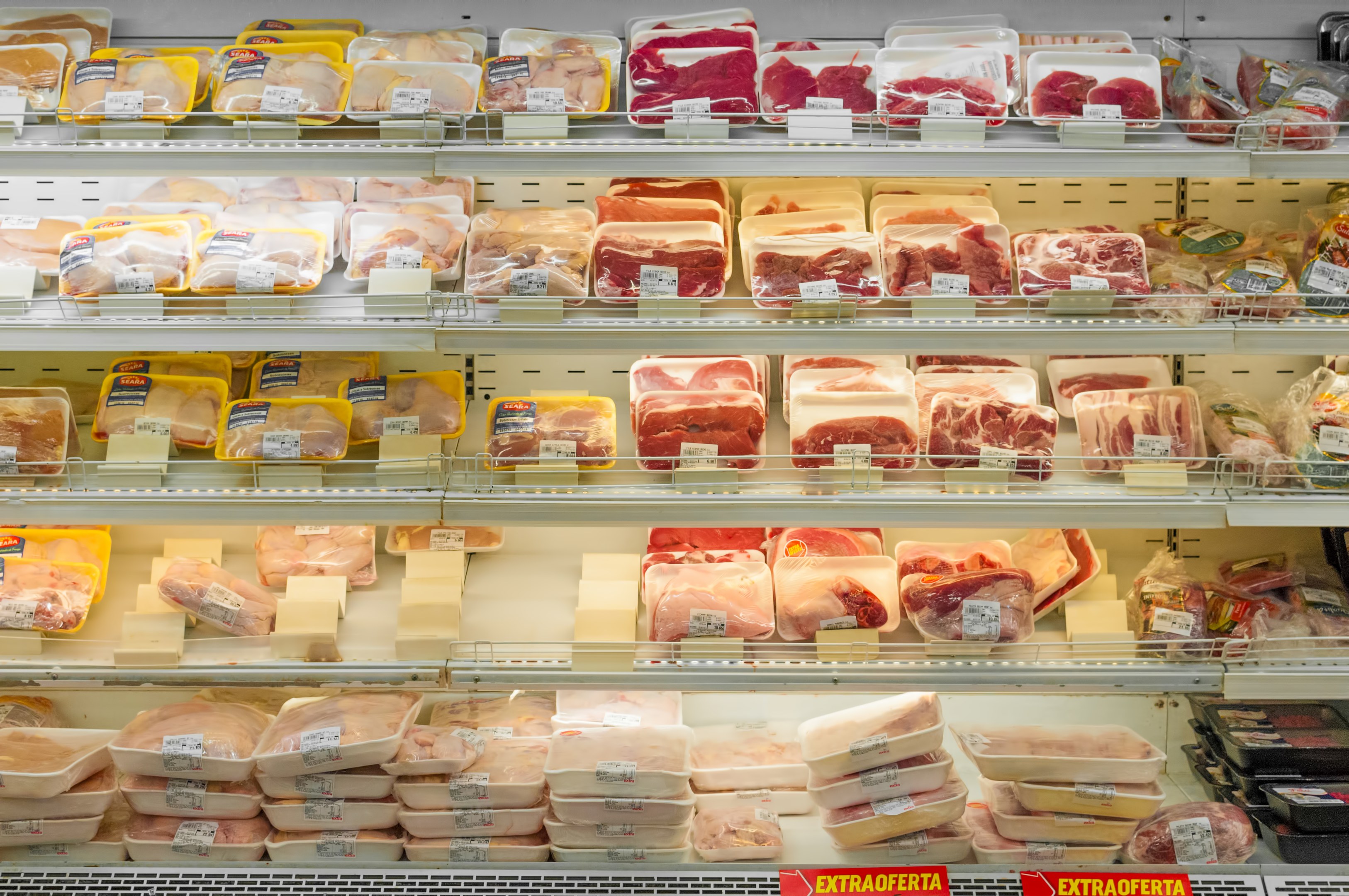 Ein gut organisierter Supermarktregal mit verschiedenen ordentlich sortierten Fleischwaren und Preisetiketten.