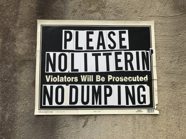 Schwarzes und weißes Schild an einem Gebäude mit der Aufschrift "Bitte Kein Müll Verunreiniger Werden Angeklagt Keine Ablagerung".