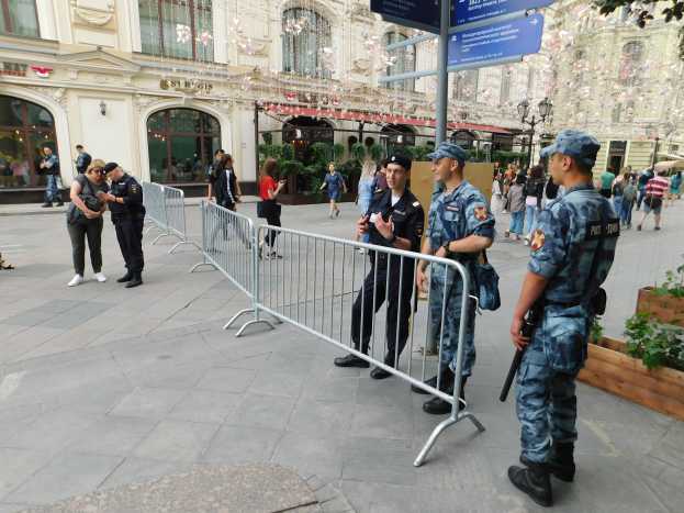 Eine Gruppe von Polizisten steht vor einer Menge, einige halten Waffen, mit Absperrungen und Texttafeln im Vordergrund und Gebäuden, Laternenmasten, Pflanzen und Bäumen im Hintergrund in Wien, Österreich während eines Anti-Terror-Einsatzes.