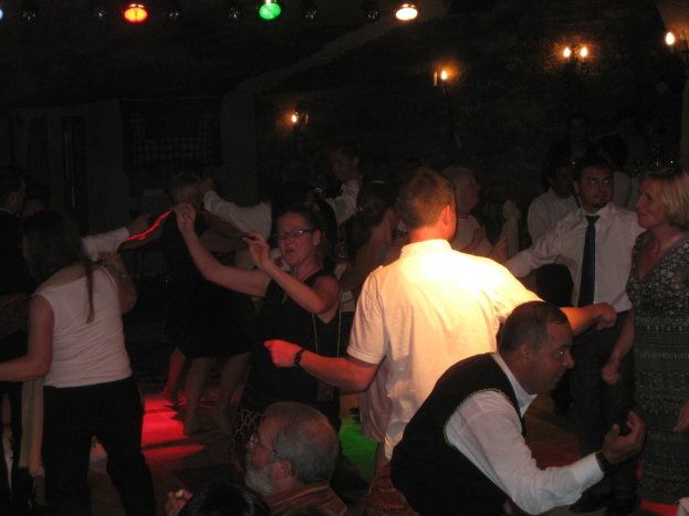 Livemusik und Tanz: Party-Szene mit tanzenden Menschen unter verschiedenen farbigen Lichtern in einem dunklen Raum.