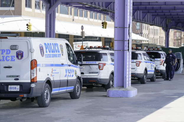 Eine Gruppe von Polizeiwagen steht am Straßenrand mit einer Person in der Nähe, Gebäude, Pfosten, Verkehrszeichen und eine Brücke im Hintergrund, wahrscheinlich im Zusammenhang mit der Boston-Marathon-Explosion.