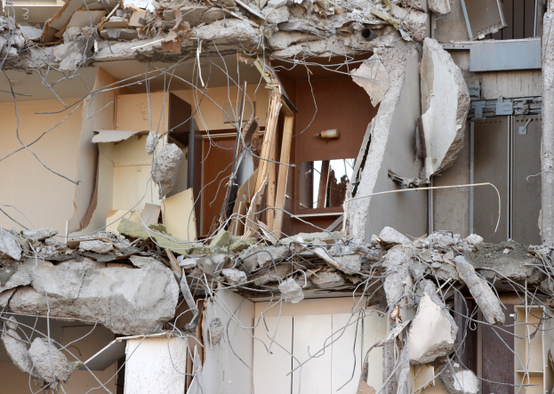 Ein teilweise abgerissenes Gebäude mit zerbrochenen Wänden und verstreuten Trümmern, einschließlich Holzstücken, in einem Zustand des Verfalls.