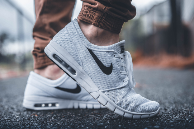 Nahaufnahme einer Person, die Nike SB Stefan Janoski Max-Schuhe in Wolf Grey/Black-White trägt, vor einem unscharfen, träumerischen Hintergrund.