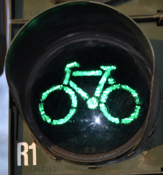 Grünes Ampelsignal mit Fahrradsymbol, das an einer Wand im Hintergrund leuchtet.