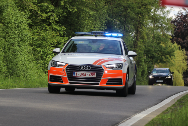 Ein Polizei-Audi A4 mit zwei Insassen, die auf einer grasbewachsenen Straße neben einem Wald fahren.