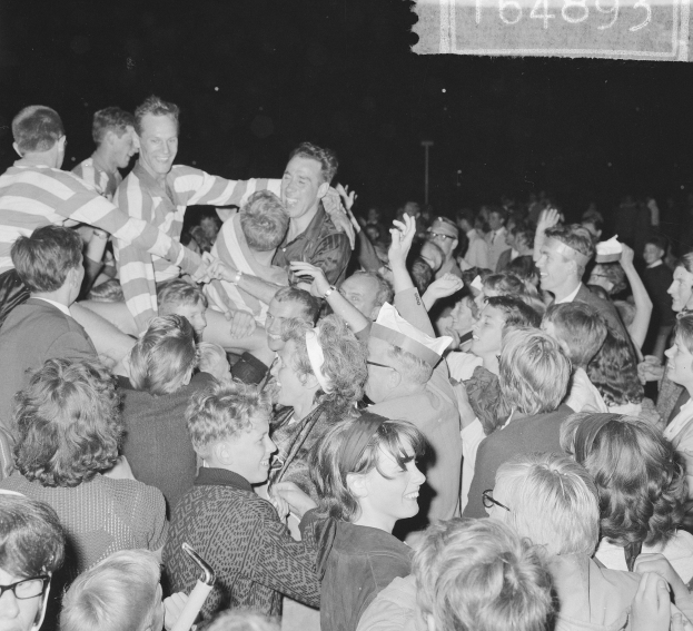 Schwarzes und weißes Foto einer Menschenmenge bei einem Konzert mit Menschen in der Mitte und Text in der oberen rechten Ecke.