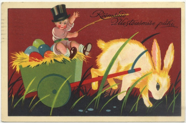 Eine alte Postkarte mit einem Baby in einem Zylinder, das einen mit bunten Ostereiern gefüllten Karren schiebt, begleitet von einem Hasen, mit Ostergruß darauf.