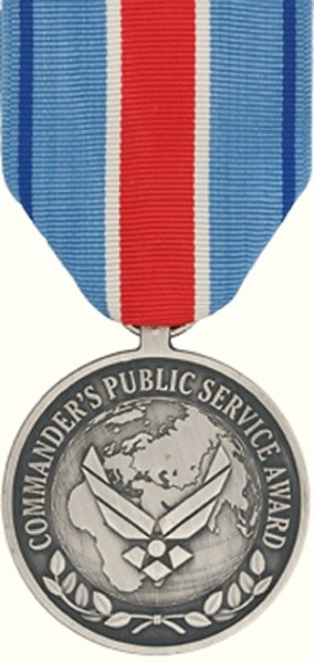 Eine Silbermedaille mit einer rot-weiß-blauen Schleife, auf der die Wörter 'Commander's Public Service Award' auf einem weißen Hintergrund zu sehen sind.