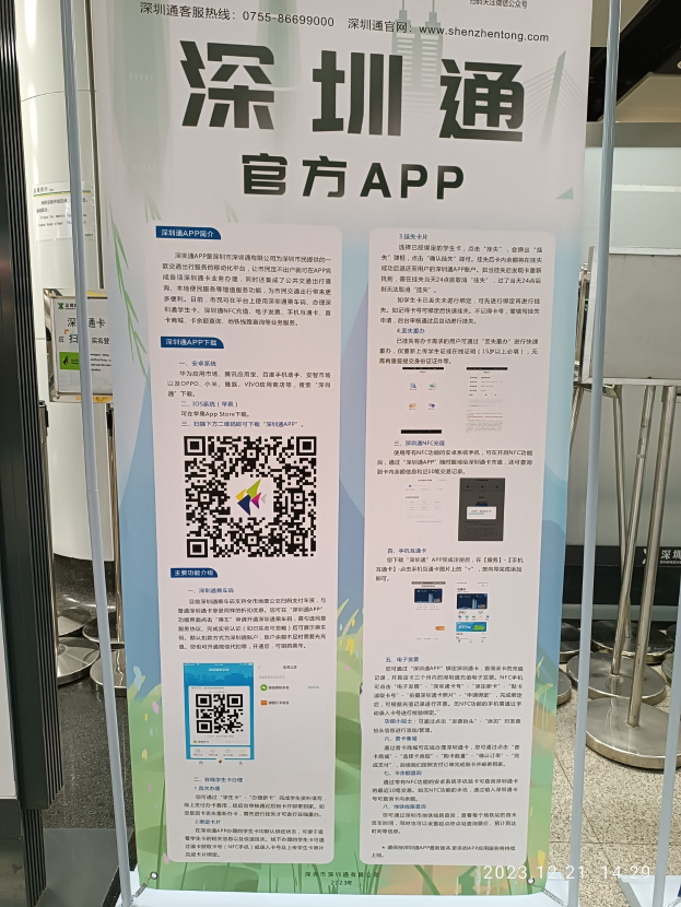 Ein Banner mit einem QR-Code vor einem Gebäude, das wahrscheinlich den Shenzhen International Airport bewirbt, umgeben von Ständen und Tafeln.