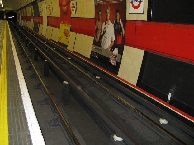 Bahnschienen mit Plakaten an der Wand.