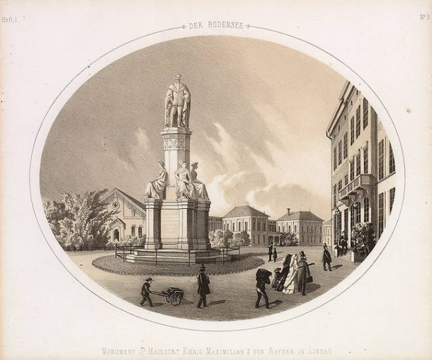 Schwarze und weiße Zeichnung der Statue des Heiligen Majestrat König Maximilian I. von Bayern in einem Stadtplatz, umgeben von Gebäuden, Bäumen und Menschen, mit Text unten und Himmel im Hintergrund.