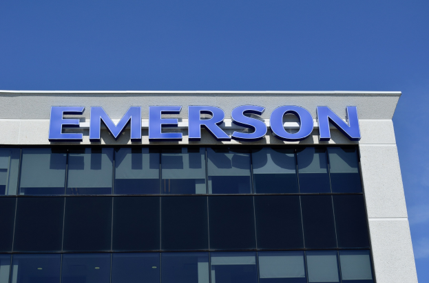 Emerson-Logo an einer Gebäudeseite mit Text, der eine Investition von 1,5 Milliarden US-Dollar in den USA ankündigt, vor einem klaren blauen Himmel.