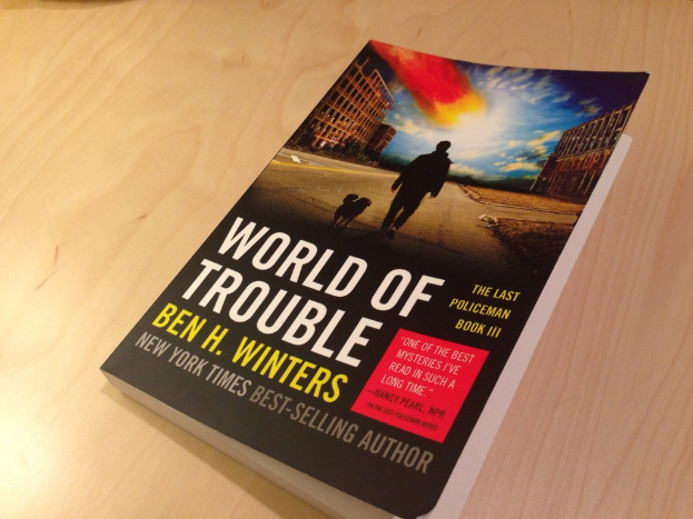 Ein Buch mit dem Titel "World Of Trouble", das ein Bild eines Mannes und eines Hundes zeigt, das auf einem Tisch liegt.
