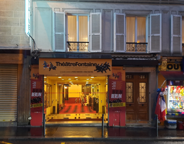Theater Fontaine in Paris, Frankreich, mit seiner Fassade mit Fenstern, Türen, einem Schild, einer Straßenlaterne, Menschen, Deckenleuchten, Regalen mit Gegenständen, einer Flagge und einer Kiste.