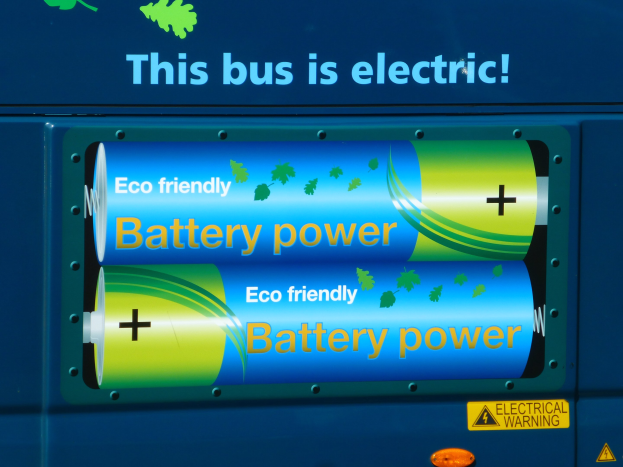 Blauer Elektrobus mit "Dieser Bus ist elektrisch"-Schriftzug und zwei sichtbaren Seitenbatterien.