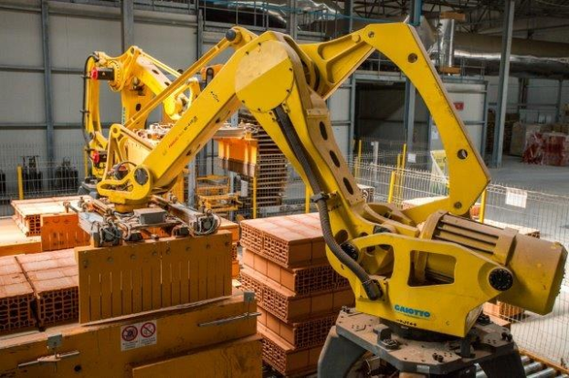 Ein große Lagerhalle voller numerous boxes, KrÄne, ein Zaun, Pfosten und andere industrielle Ausrütung, mit einer Wand im Hintergrund.