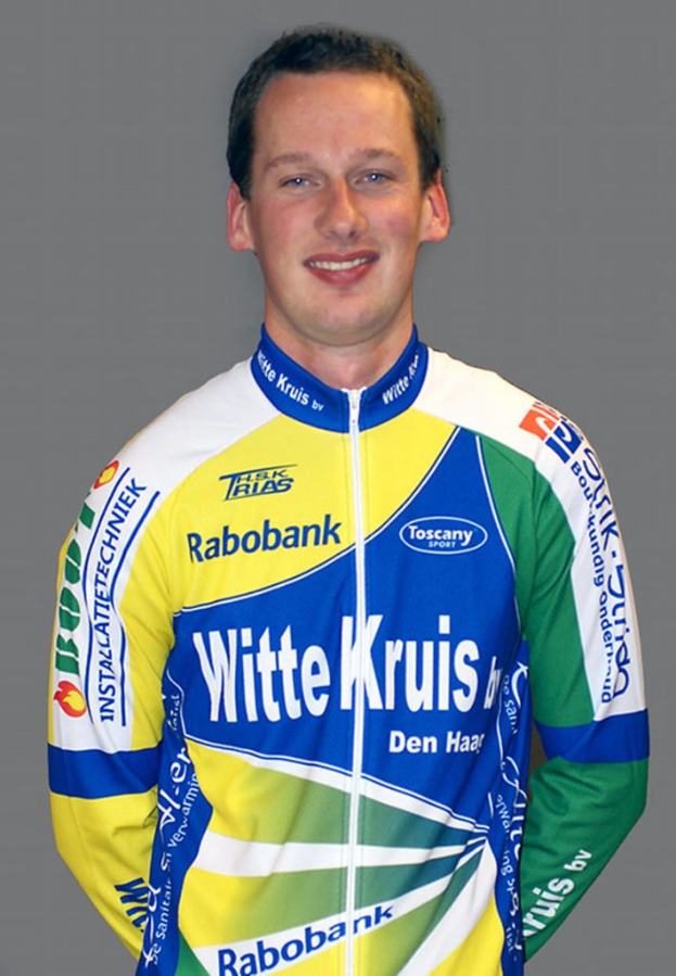 Ein männlicher Athlet posiert für ein Foto, trägt ein Hemd mit Namen mehrerer Sponsorenfirmen.