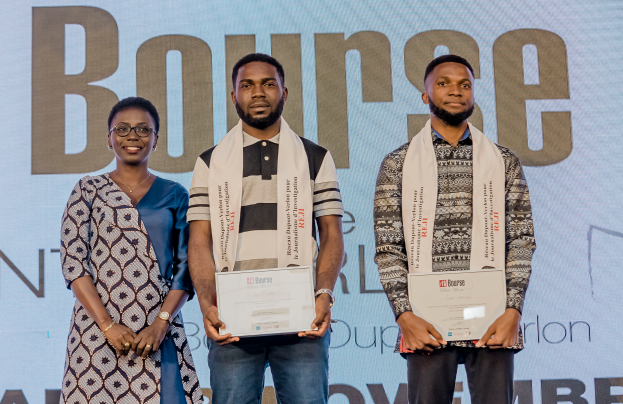 Drei Personen stehen auf einer Bühne und halten Zertifikate in den Händen, hinter ihnen ist ein Bildschirm mit der Aufschrift "Bounce Africa Awards 2019."