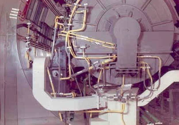 Große industrielle Beschleuniger-Maschine mit mehreren verbundenen Komponenten und Kabeln innerhalb eines Gebäudes.