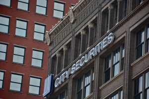 Ein hohes Gebäude mit vielen Fenstern, ein "Stadt-Sicherheiten"-Schild an der Seite und ein Namensschild mit Text.