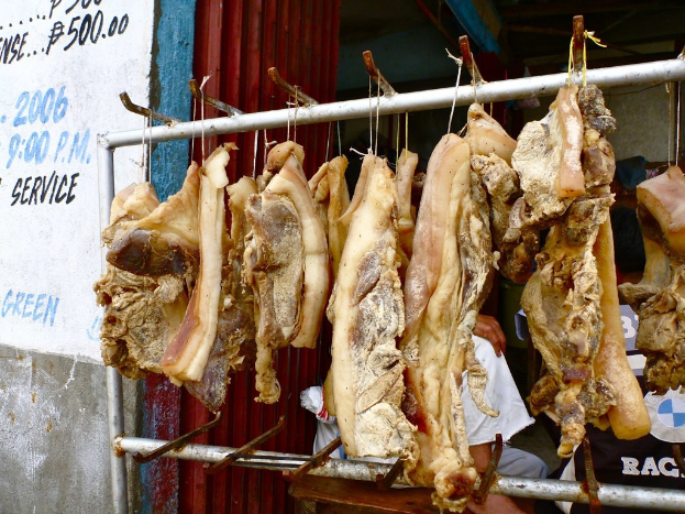 Fleisch an einem Ständer mit einer Person dahinter und einer Wand mit Text links daneben.