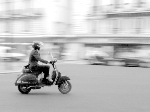 Eine Person fährt auf einem Scooter auf der Straße.