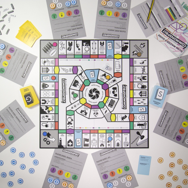 Ein Monopoly-Brettspiel auf einem Tisch mit verstreuten Spielkarten, Papieren und einem Bleistift, das Brett und die Teile zum Spielen ausgelegt.