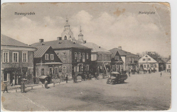 Schwarzer und weißer Fotograf einer Straße in Nowogrodziec, Deutschland, mit Gebäuden, Menschen, Wagen, Pfählen, Bäumen und Himmel, mit dem Text "Marktplatz in Nowogrodeek, Deutschland" oben und unten.