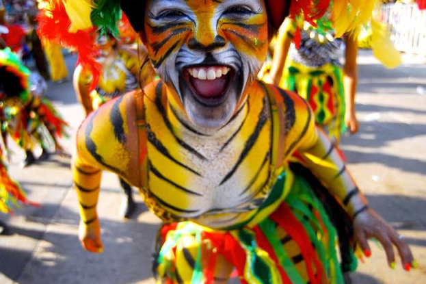 Eine Gruppe von Menschen in bunten Kostümen und Schminke bei einem Karneval, mit einer Frau in einem Tigerkostüm im Vordergrund und einem unscharfen Hintergrund.