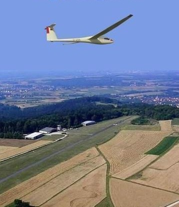 Segelflug über einem Feld mit Bäumen und Gebäuden im Hintergrund, mit Text oben.