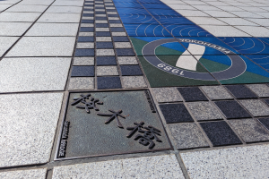 Ein gefliesteter Boden mit einem Schild, auf dem "Yokohama" steht, und einer Tafel mit Text darauf.
