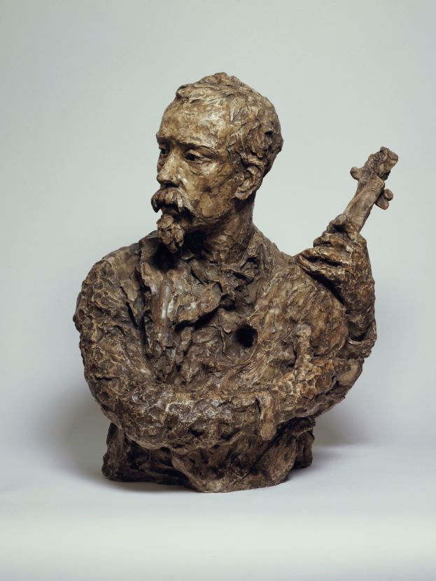 Eine Bronzestatue eines bärtigen Mannes mit einer Gitarre, die "Der Gitarrenspieler" genannt wird, vor einem weißen Hintergrund.