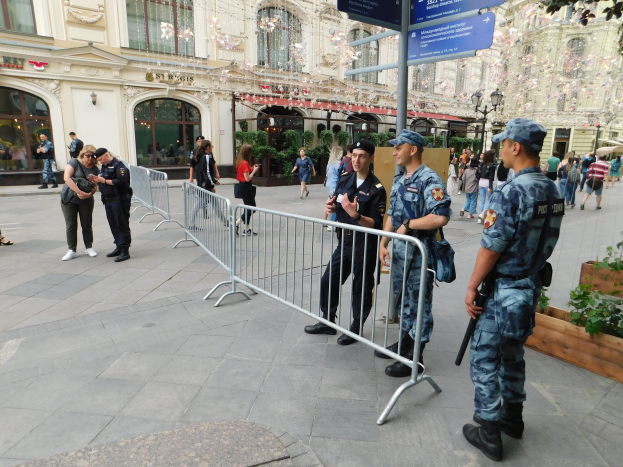 Polizeibeamte in Uniform stehen hinter Absperrungen und blicken auf eine Menge, einige halten Waffen, mit Schildern und Gebäuden im Hintergrund während einer Anti-Terror-Operation in Wien, Österreich.