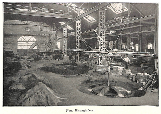 Schwarzes und wei├čes Foto einer Fabrik mit Arbeitern an einer Maschine, umgeben von Metallstangen und -rohren, mit der Beschriftung 'Neue Eisenglebeerei, die erste Fabrik Deutschlands' unten.