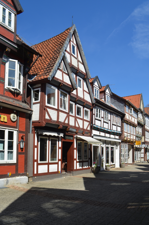Eine Kopfsteinpflasterstraße in Heidelbergs Altstadt mit Gebäuden im Vordergrund, einem klaren blauen Himmel im Hintergrund und einer Straßenlaterne auf der linken Seite.