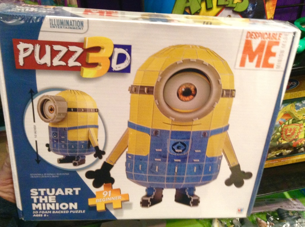 Ein RÃ¤tselkasten mit einem Spielzeugabbild darauf, mit anderen Spielzeugen im Hintergrund.