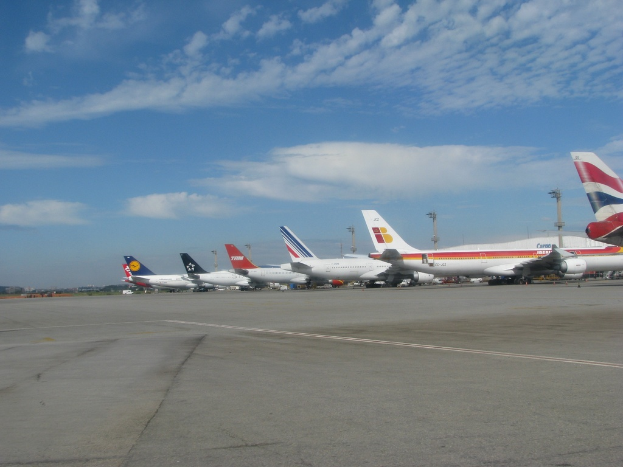 Eine Start- und Landebahn mit einigen Flugzeugen, Pfählen, Kabeln und einer bewölkten Himmel.