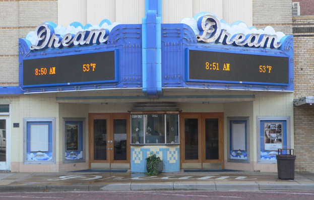 Außenansicht des Dream Theaters in St. Louis, Missouri, mit Glastüren und -fenstern, einem Namen-Schild, einem Müllbehälter, einem Topf mit einer Pflanze und einer Straße unten.